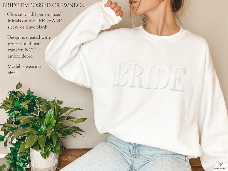K&ouml;nnte beinhalten: Wei&szlig;er Crewneck-Pullover mit dem Wort "BRIDE" auf der Vorderseite. Der Pullover wird von einem Model getragen.