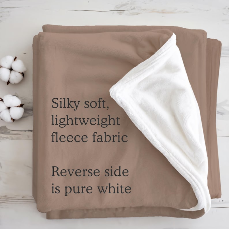 May include: A soft, lightweight fleece blanket in a warm brown color, with a pure white reverse side. The text on the blanket reads: "Silky soft, lightweight fleece fabric. Reverse side is pure white."