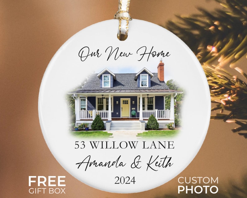 May include: White ceramic ornament with a photo of a blue house with white trim and a green lawn. The text "Our New Home", "53 Willow Lane", "Amanda & Keith", and "2024" is printed on the ornament.