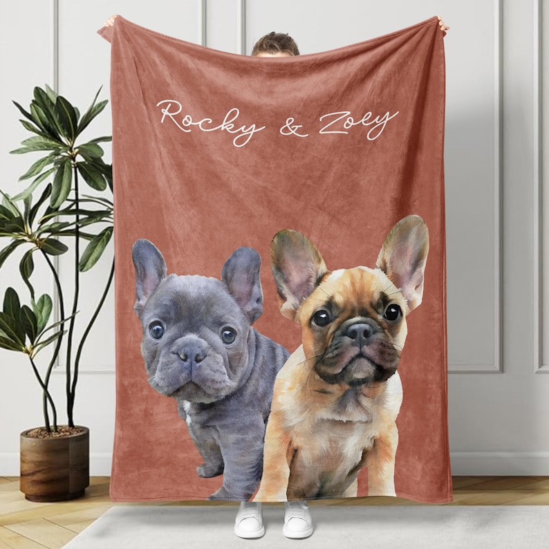 May include: A terracotta-colored blanket featuring two French Bulldogs. One is gray, the other is tan. The blanket has the text "Rocky & Zoey" in white script across the top.