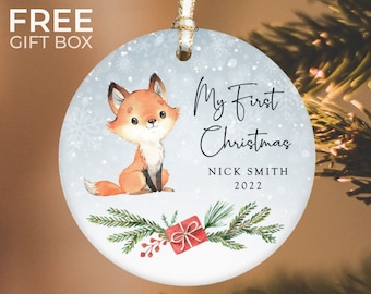 May include: A blue and white Christmas bauble featuring a cute fox illustration, a red gift box, and the text "My First Christmas Nick Smith 2022".