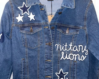 May include: A blue denim jacket with white and navy blue star appliques and the words "nittany lions" embroidered on the front.