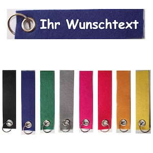 May include: Ten felt keychains in various colors, including black, blue, green, gray, pink, red, orange, and yellow. Each keychain has a silver metal ring.