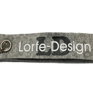 May include: Grey felt keyring with a silver key ring and the text "Lorfe-Design" in white lettering with a black "LD" logo.