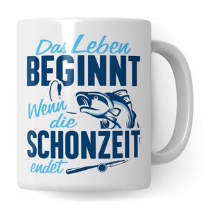 Op de afbeelding: Witte keramische mok met een blauw-witte afbeelding van een vis en een hengel. De mok heeft de Duitse tekst "Das Leben BEGINNT Wenn die SCHONZEIT endet" in blauw. De mok heeft een wit handvat.
