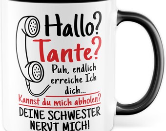 Può includere: Tazza in ceramica bianca con bordo e manico neri. La tazza presenta un'illustrazione in bianco e nero di un telefono a disco con il testo "Hallo? Tante? Puh, endlich erreiche Ich dich... Kannst du mich abholen? DEINE SCHWESTER NERVT MICH!" in rosso e nero.