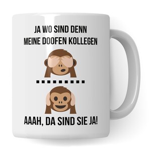 May include: White ceramic coffee mug with a black and brown illustration of two monkeys. The top monkey is covering its eyes and the bottom monkey is covering its ears. The text on the mug reads "JA WO SIND DENN MEINE DOOFEN KOLLEGEN" and "AAAAH, DA SIND SIE JA!"