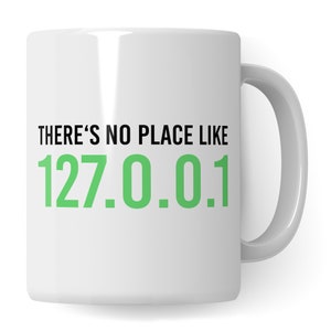 Può includere: Tazza in ceramica bianca con testo nero che recita "THERE'S NO PLACE LIKE 127.0.0.1" in verde.