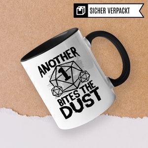 May include: White ceramic mug with a black handle. The mug has a black and white graphic of a dice with the number one on it and the text "Another Bites The Dust".