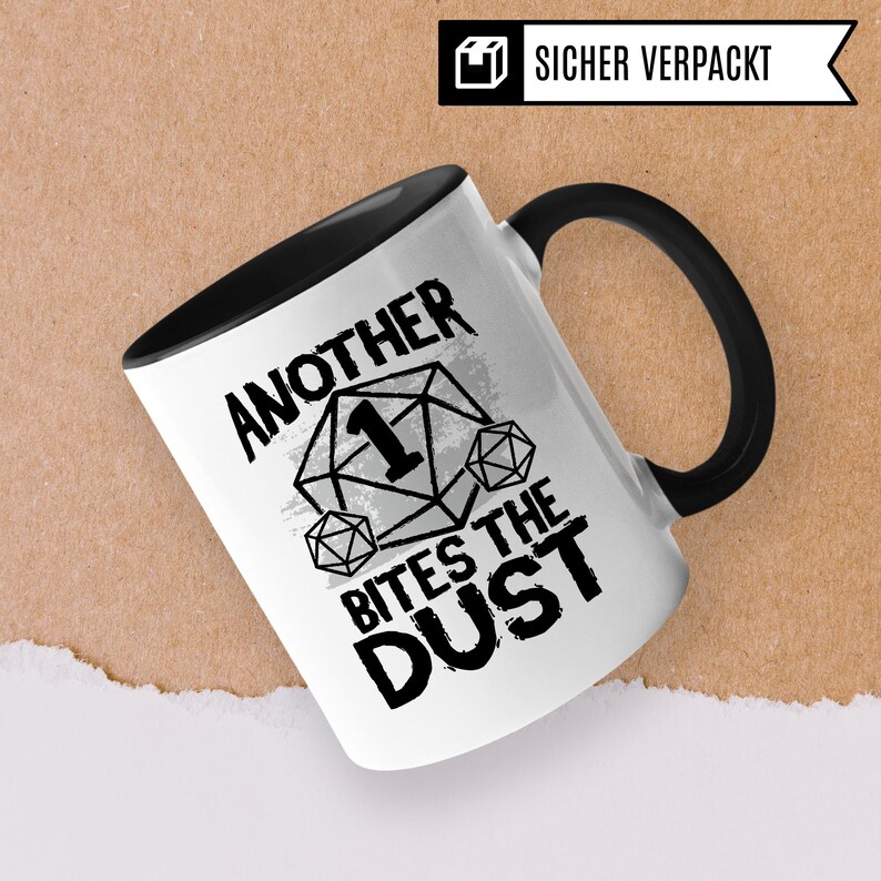 May include: White ceramic mug with a black handle. The mug has a black and white graphic of a dice with the number one on it and the text "Another Bites The Dust".