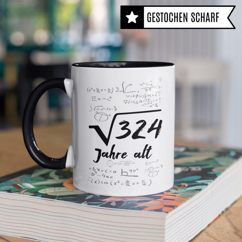 May include: White ceramic mug with a black handle. The mug has black text and mathematical equations printed on it. The text reads "&radic;324 Jahre alt".