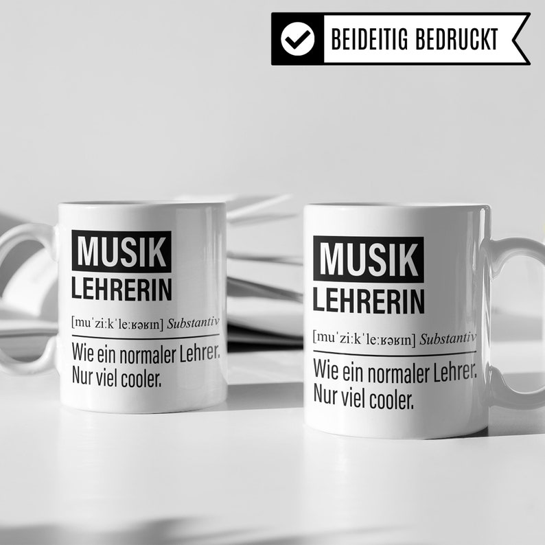 May include: Two white ceramic mugs with black text that reads "MUSIK LEHRERIN [mu'zi:k'le:kərın] Substantiv Wie ein normaler Lehrer. Nur viel cooler."