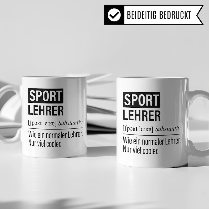 May include: Two white ceramic mugs with black text that reads "SPORT LEHRER [sport le:re] Substantiv Wie ein normaler Lehrer. Nur viel cooler."