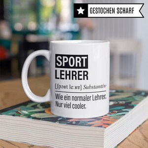 May include: White ceramic mug with a black design that reads "SPORT LEHRER [sport le:ke] Substantiv Wie ein normaler Lehrer. Nur viel cooler."
