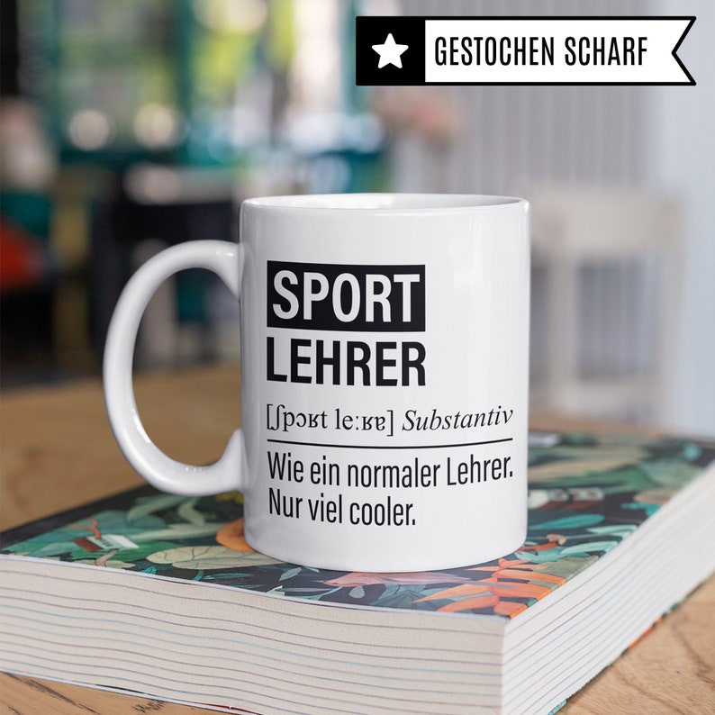 May include: White ceramic mug with a black design that reads "SPORT LEHRER [sport le:ke] Substantiv Wie ein normaler Lehrer. Nur viel cooler."