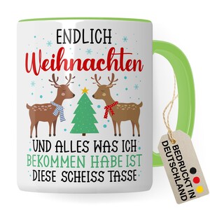 Könnte beinhalten: Weiße Keramiktasse mit grünem Rand und Henkel. Die Tasse zeigt ein weihnachtliches Design mit zwei Rentieren, einem Weihnachtsbaum und dem Text "ENDLICH Weihnachten UND ALLES WAS ICH BEKOMMEN HABE IST DIESE SCHEISS TASSE". Ein braunes Etikett mit dem Text "BEDRUCKT IN DEUTSCHLAND" ist am Henkel befestigt.