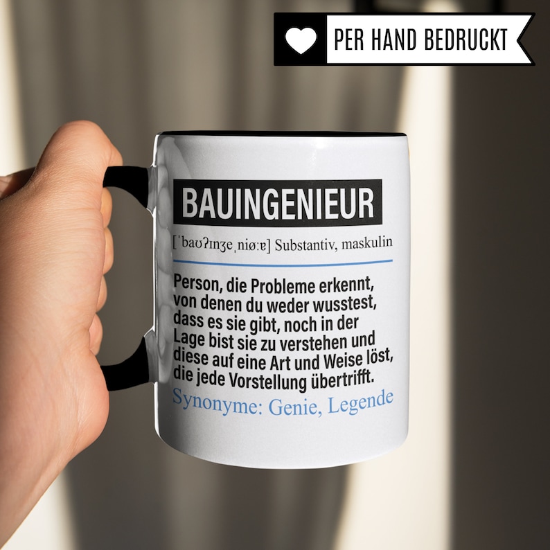 May include: White ceramic mug with a black handle and rim. The mug features a black and white graphic with the word "BAUINGENIEUR" in bold, followed by a definition in German. The text reads: "['bao?nze, ni&oslash;:e] Substantiv, maskulin Person, die Probleme erkennt, von denen du weder wusstest, dass es sie gibt, noch in der Lage bist sie zu verstehen und diese auf eine Art und Weise l&ouml;st, die jede Vorstellung &uuml;bertrifft. Synonyme: Genie, Legende"