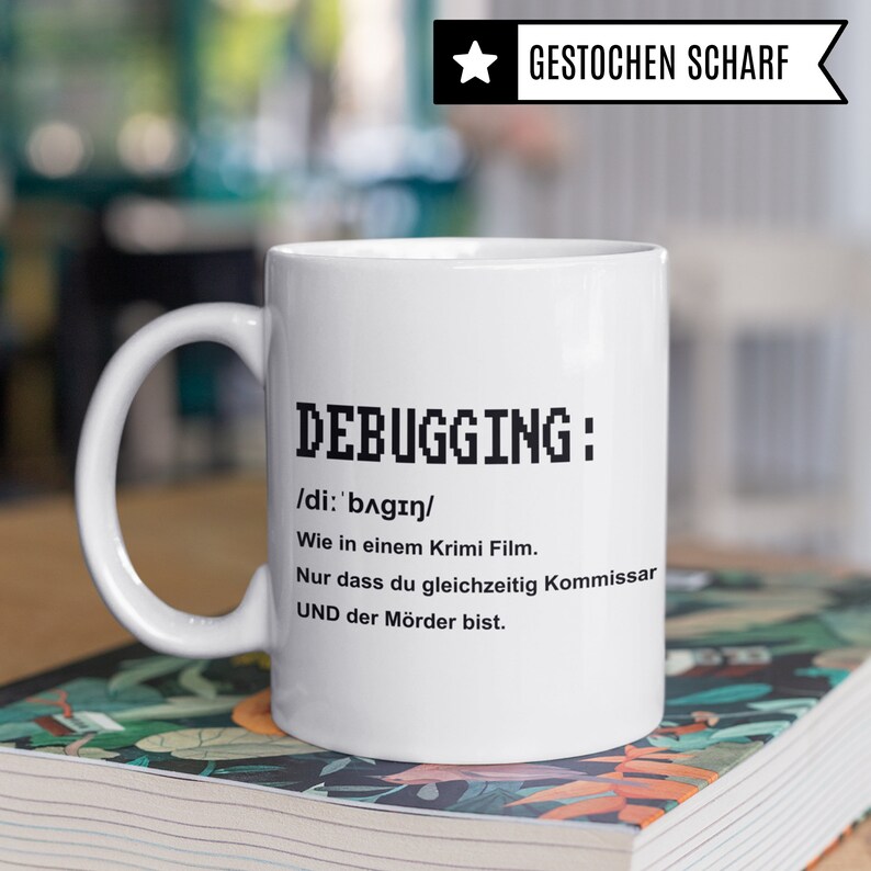 K&ouml;nnte beinhalten: Wei&szlig;e Keramiktasse mit schwarzem Text, der "DEBUGGING: /di: 'bagin/ Wie in einem Krimi Film. Nur dass du gleichzeitig Kommissar UND der M&ouml;rder bist." lautet.