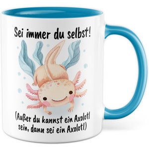 May include: White ceramic mug with a blue rim and handle. The mug features a cartoon illustration of an axolotl with the text "Sei immer du selbst! (Au&szlig;er du kannst ein Axolotl sein, dann sei ein Axolotl)"