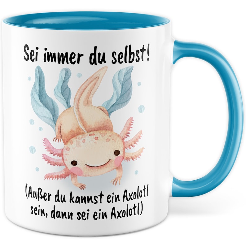 May include: White ceramic mug with a blue rim and handle. The mug features a cartoon illustration of an axolotl with the text "Sei immer du selbst! (Au&szlig;er du kannst ein Axolotl sein, dann sei ein Axolotl)"