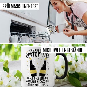 May include: White ceramic coffee mug with a black handle. The mug has a black and white design with a graphic of two champagne bottles and the text "Ich habe e Mikrowellenbest&auml;ndig Doktortitel" and "Lasst uns einfach annehmen, dass ich immer recht habe."