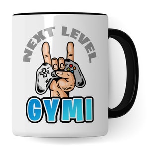 Könnte beinhalten: Eine weiße Keramik-Kaffeetasse mit schwarzem Henkel. Die Tasse zeigt eine graue Grafik einer Hand, die einen Videospielcontroller hält, mit dem Text "NEXT LEVEL GYMI" in Grau und Blau.