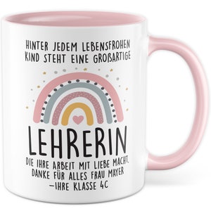 Könnte beinhalten: Weiße Keramiktasse mit rosafarbenem Rand und Henkel. Die Tasse zeigt einen Regenbogen mit einem Herzen in der Mitte und den Text "HINTER JEDEM LEBENSFROHEN KIND STEHT EINE GROßARTIGE LEHRERIN DIE IHRE ARBEIT MIT LIEBE MACHT. DANKE FÜR ALLES FRAU MAYER -IHRE KLASSE 4C"