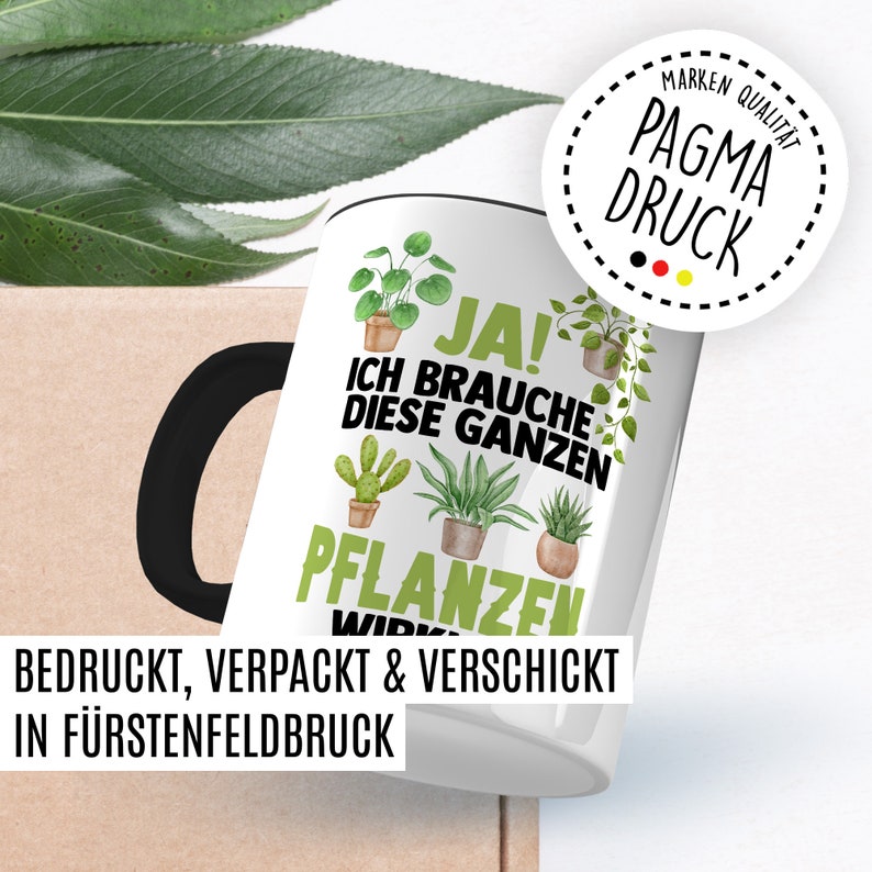 May include: White ceramic mug with a black handle. The mug features a watercolor illustration of various potted plants and the text "JA! ICH BRAUCHE DIESE GANZEN PFLANZEN" in black. The text "BEDRUCKT, VERPACKT & VERSCHICKT IN F&Uuml;RSTENFELDBRUCK" is printed on the bottom of the mug.