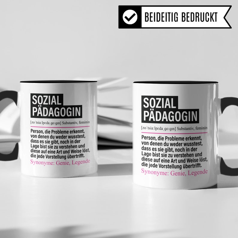 May include: Two white mugs with black handles and black rims. The mugs have a black and pink graphic with the text "SOZIAL P&Auml;DAGOGIN" and a definition of the word in German. The text on the mugs reads "[zo'tsia:lpeda go:gin] Substantiv, feminin Person, die Probleme erkennt, von denen du weder wusstest, dass es sie gibt, noch in der Lage bist sie zu verstehen und diese auf eine Art und Weise l&ouml;st, die jede Vorstellung &uuml;bertrifft. Synonyme: Genie, Legende"