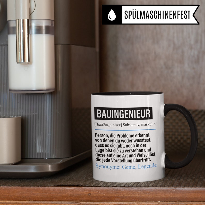 May include: A white coffee mug with a black handle and rim. The mug has black text that reads "BAUINGENIEUR ['bao?inze, ni&oslash;re] Substantiv, maskulin Person, die Probleme erkennt, von denen du weder wusstest, dass es sie gibt, noch in der Lage bist sie zu verstehen und diese auf eine Art und Weise l&ouml;st, die jede Vorstellung &uuml;bertrifft. Synonyme: Genie, Legende"