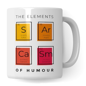 Pode incluir: Caneca de cerâmica branca com um contorno preto dos elementos da tabela periódica, com os símbolos químicos S, Ar, Ca e Sm. O texto "THE ELEMENTS OF HUMOUR" está impresso abaixo da tabela.