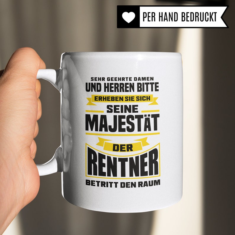 Puede incluir: Taza de cer&aacute;mica blanca con un dise&ntilde;o en negro y amarillo que dice "Sehr geehrte Damen und Herren bitte erheben Sie sich Seine Majest&auml;t der Rentner betritt den Raum".