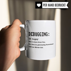 K&ouml;nnte beinhalten: Wei&szlig;e Keramiktasse mit einer schwarzen Grafik, auf der steht: "DEBUGGING: /di: bagin/ Wie in einem Krimi Film. Nur dass du gleichzeitig Kommissar UND der M&ouml;rder bist."