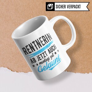 May include: White ceramic mug with a blue and black graphic that says "Rentnerin ab jetzt auch montags gut gelaunt".