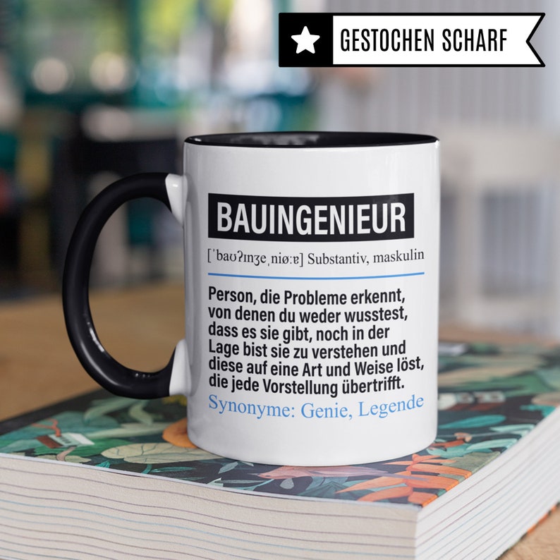 May include: White ceramic mug with a black handle and black rim. The mug has a black and white design with the text "BAUINGENIEUR ['bao?inze, nio:e] Substantiv, maskulin Person, die Probleme erkennt, von denen du weder wusstest, dass es sie gibt, noch in der Lage bist sie zu verstehen und diese auf eine Art und Weise l&ouml;st, die jede Vorstellung &uuml;bertrifft. Synonyme: Genie, Legende"