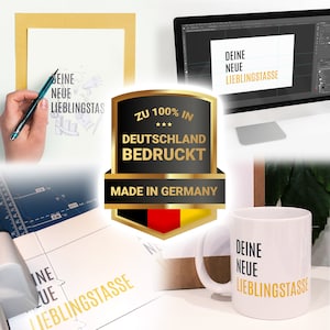 May include: A white ceramic mug with the text "DEINE NEUE LIEBLINGSTASSE" in gold lettering. The mug is sitting on a brown cardboard box. A computer monitor in the background displays the same text. A gold seal with the text "ZU 100% IN DEUTSCHLAND BEDRUCKT MADE IN GERMANY" is visible in the image.