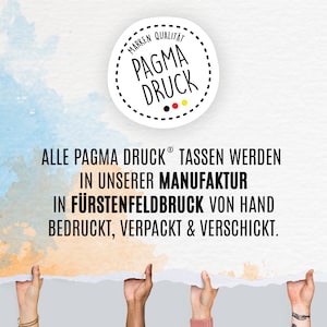 May include: A white circle with black dashed lines around the edge and the text "MARKEN QUALITAT PAGMA DRUCK" in black. The circle is on a light blue and orange watercolour background. The text "ALLE PAGMA DRUCK&reg; TASSEN WERDEN IN UNSERER MANUFAKTUR IN F&Uuml;RSTENFELDBRUCK VON HAND BEDRUCKT, VERPACKT & VERSCHICKT." is below the circle.