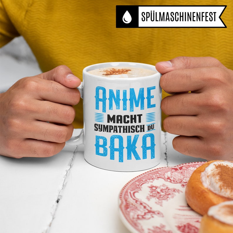 May include: White coffee mug with blue text that reads "Anime Macht Sympathisch Du Baka".
