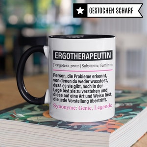 May include: White ceramic mug with a black handle and black rim. The mug features a black and white graphic with the text "ERGOTHERAPEUTIN" and a definition in German. The text "GESTOCHEN SCHARF" is in a star shape at the top of the mug.