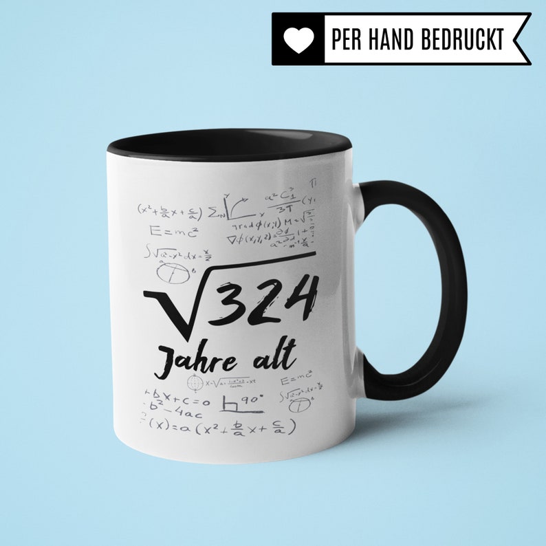 May include: White ceramic mug with a black handle and rim. The mug features a black and white design of mathematical equations and the text "&radic;324 Jahre alt". The text "PER HAND BEDRUCKT" is printed in black on a white heart shape.