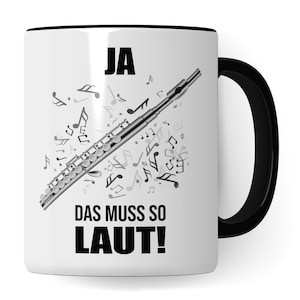Könnte beinhalten: Weiße Keramiktasse mit schwarzem Rand und Henkel. Die Tasse zeigt eine Schwarzweißillustration einer Flöte mit Noten und dem Text "JA DAS MUSS SO LAUT!"