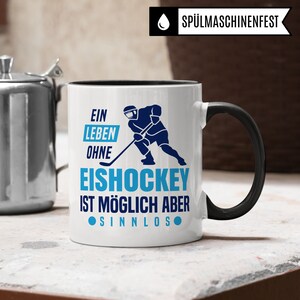 Pu&ograve; includere: Tazza in ceramica bianca con manico e bordo neri. La tazza presenta un'illustrazione blu e nera di un giocatore di hockey con un bastone e un disco. Il testo sulla tazza recita "Ein Leben Ohne Eishockey Ist M&ouml;glich Aber Sinnlos".