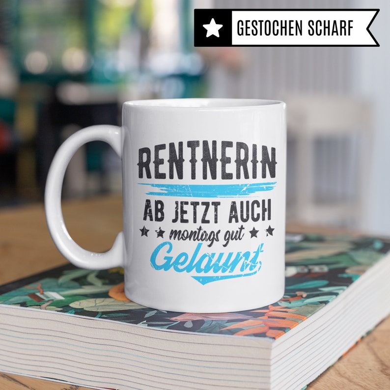 May include: White ceramic mug with a blue and black design that says "Rentnerin ab jetzt auch montags gut Gelaunt".