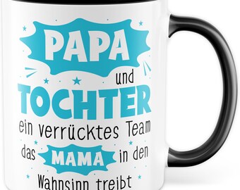 Può includere: Tazza in ceramica bianca con bordo e manico neri. La tazza ha un design blu con il testo "Papa und Tochter ein verrücktes Team das Mama in den Wahnsinn treibt".