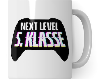 Könnte beinhalten: Weiße Keramiktasse mit einem schwarz-weißen Grafikdesign einer Videospielkonsole. Der Text "NEXT LEVEL 5. KLASSE" ist in einer Glitch-Schriftart auf die Tasse gedruckt.