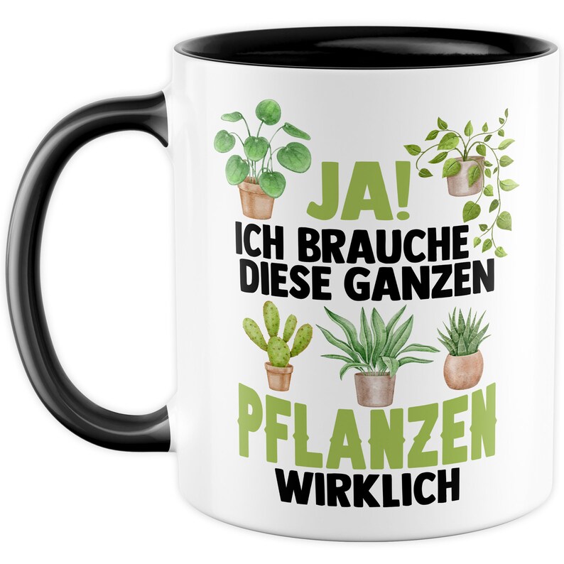 May include: White ceramic mug with a black handle and black rim. The mug features a green and white illustration of various potted plants and the text "JA! ICH BRAUCHE DIESE GANZEN PFLANZEN WIRKLICH".