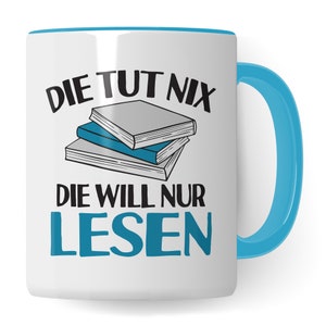 Könnte beinhalten: Weiße Keramiktasse mit blauem Rand und Henkel. Die Tasse zeigt eine Schwarzweißillustration eines Bücherstapels und den Text "Die tut nix die will nur lesen".