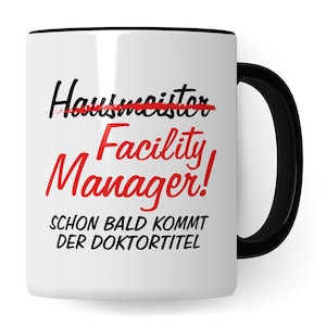 Könnte beinhalten: Weiße Keramiktasse mit schwarzem Rand und Henkel. Die Tasse hat einen roten Strich durch das Wort "Hausmeister" und die Worte "Facility Manager!" in rot. Unter dem Text steht der Satz "Schon bald kommt der Doktortitel" in schwarz.