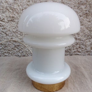 May include: White glass table lamp with a mushroom-shaped shade and a gold base.