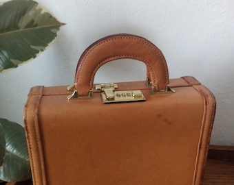 May include: A brown leather briefcase with a gold handle and a combination lock. The lock has the numbers 666 on it.